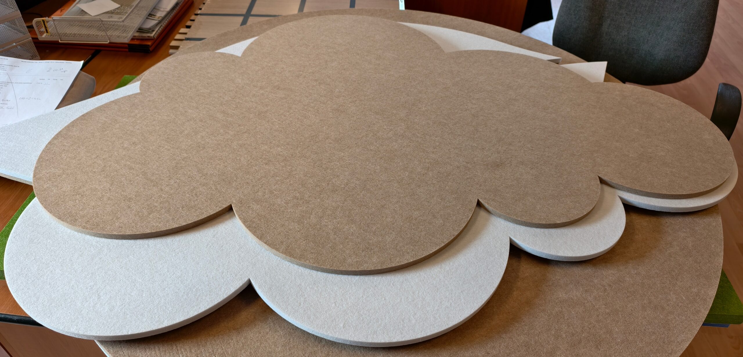 Paneles acústicos Bilnora con forma de nube apilados en blanco y camel