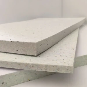 Primer plano de varias placas de Elitexa espuma insonorizante ignífuga apiladas, con cantos rectos, grosor visible y superficie clara con pequeñas motas de color.