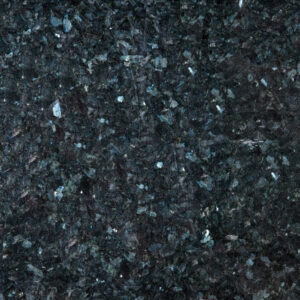 Primer plano del granito natural Blue Pearl, con una superficie oscura de tonos azulados, negros y grises y reflejos minerales más claros distribuidos de forma irregular.